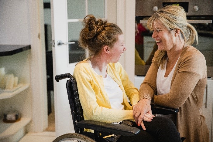 Dec update person in wheelchair lauging with person in beige cardigan