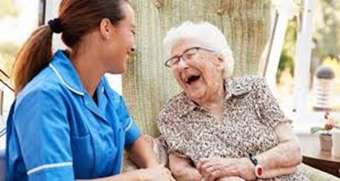 sept elderly person laughing with carer in blue uniform