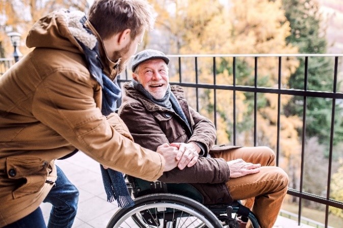 Gentleman with beard in wheelchair with carer