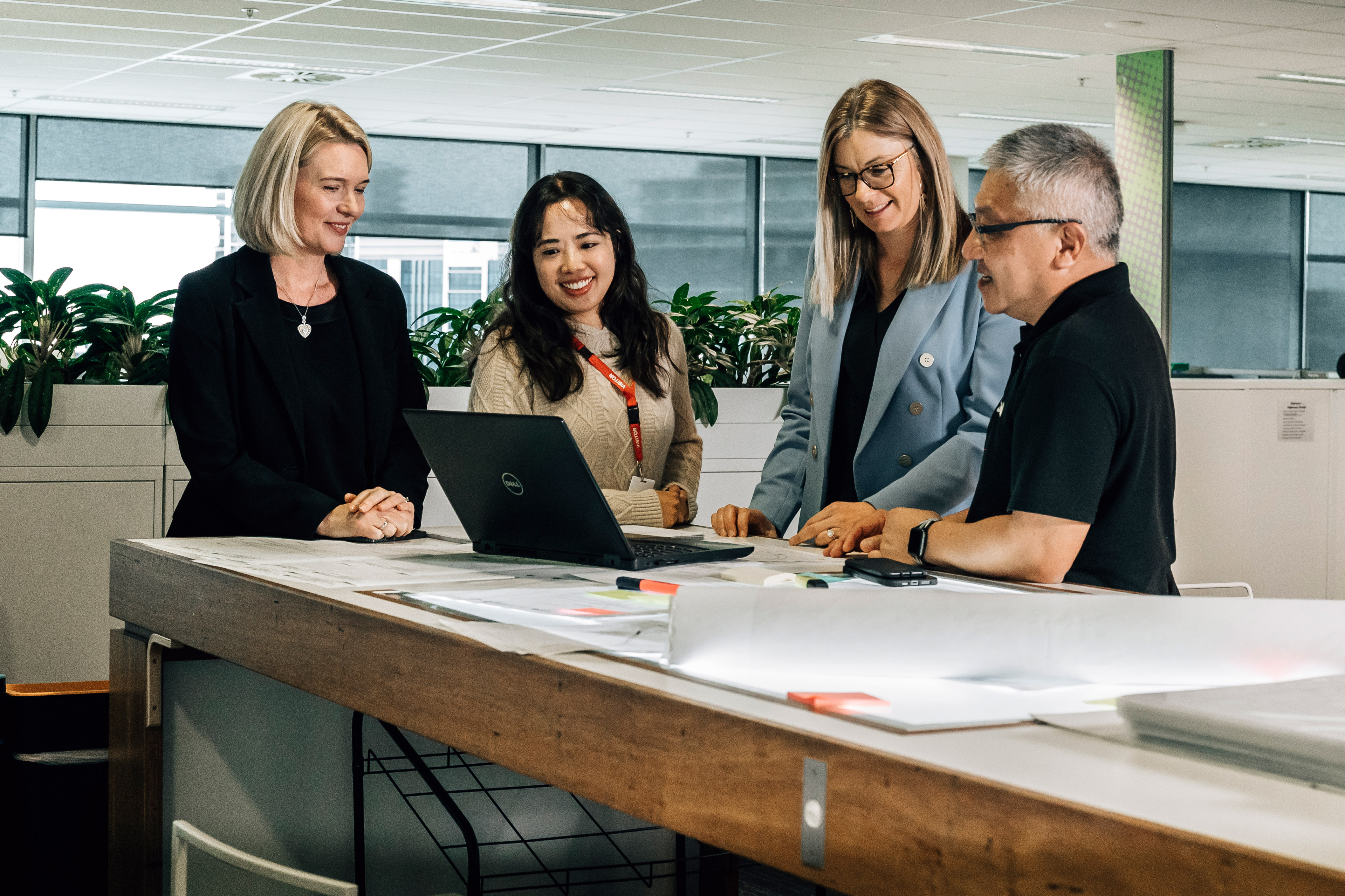 Group of four people standing around a laptop