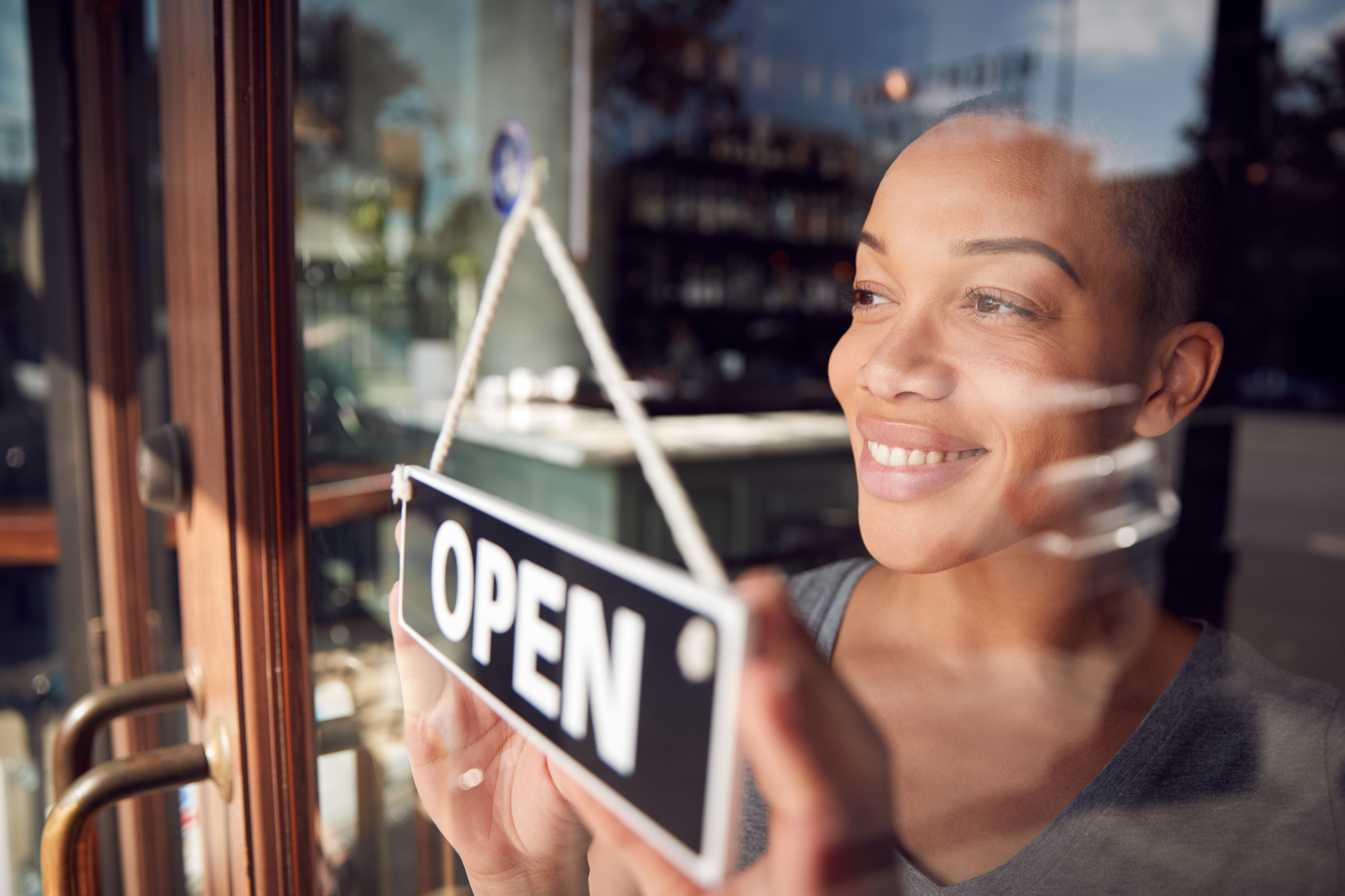 Woman turning an open-closed sign on a glass entry door