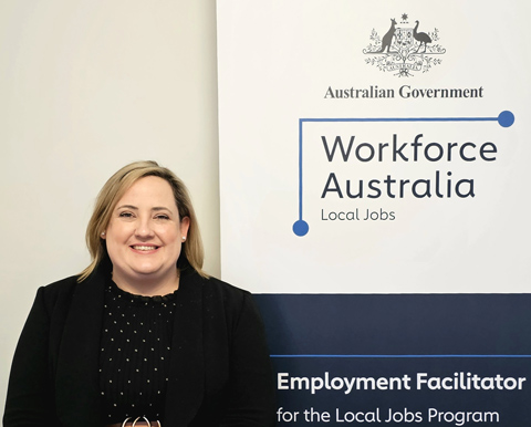 Andrea Wynne, the Employment Facilitator for Esperance smiling at the camera while standing in front of Workforce Australia banner.