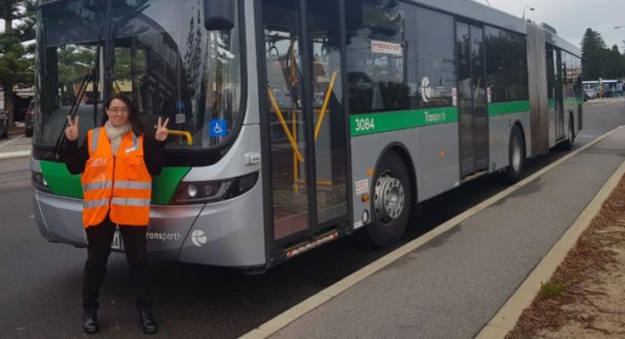 Woman standing in front of bus giving with hands up in a peace sign