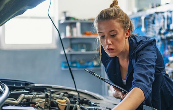 Young female mechanic is checking under the bonnet of a car.