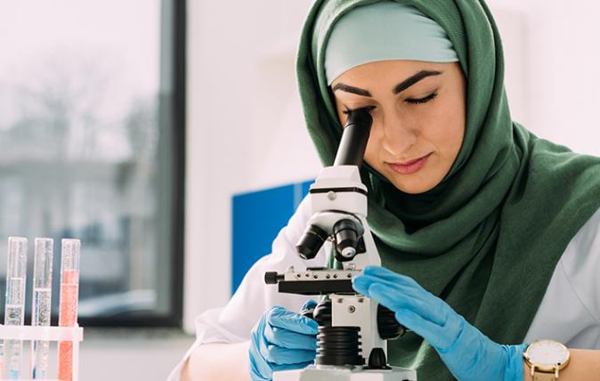 Young female looking through a micoscope