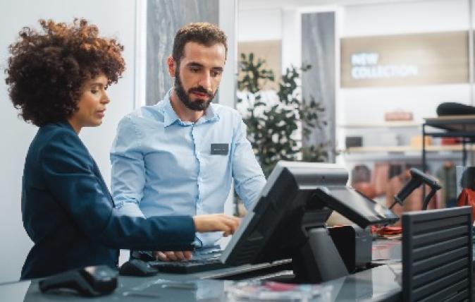 Image of two people standing behind a cash register