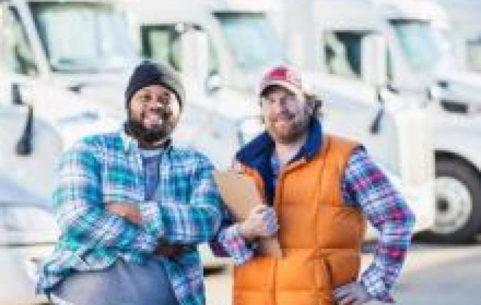 2 people standing in front of a line up of trucks