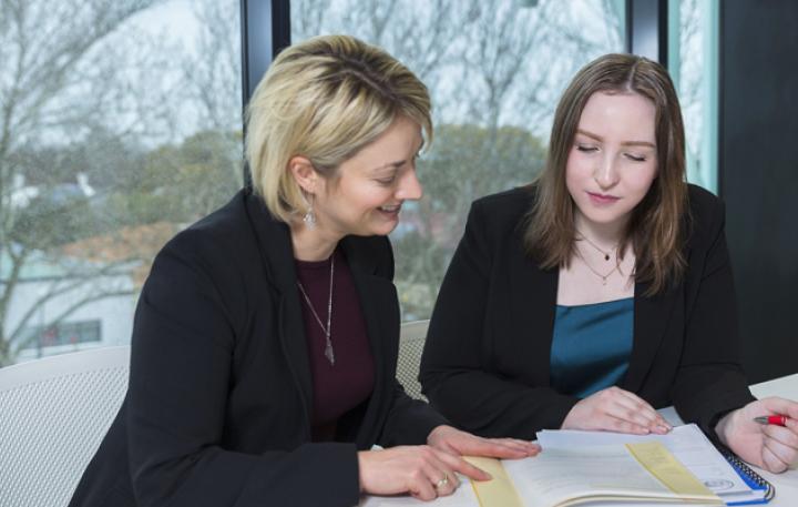 Older female and younger female working at a desk reviewing documents 