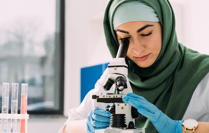 Young female looking through a micoscope