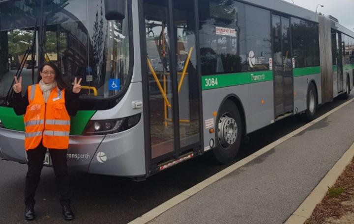 Woman standing in front of bus giving with hands up in a peace sign