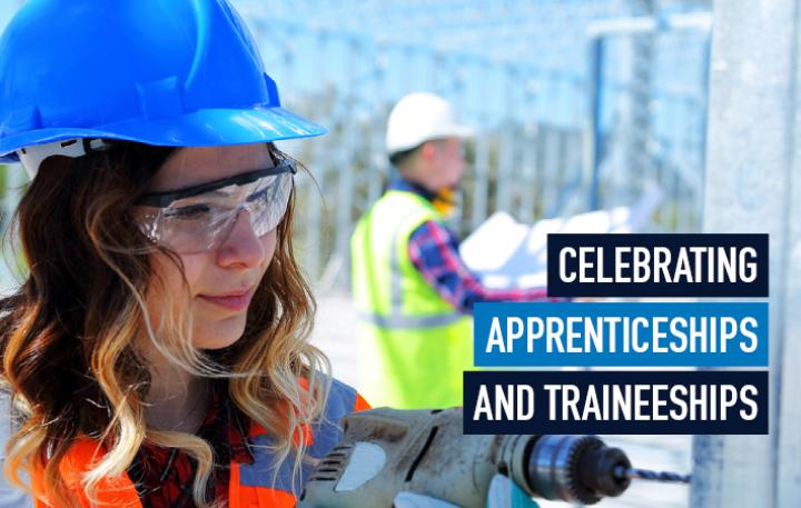 A young woman wearing a high-visibility vest and a blue safety helmet is on a work site drilling into a wall while a man in a similar outfit examines a layout document in the background. Superimposed next to the woman is the title 'Celebrating Apprenticeships and Traineeships'.