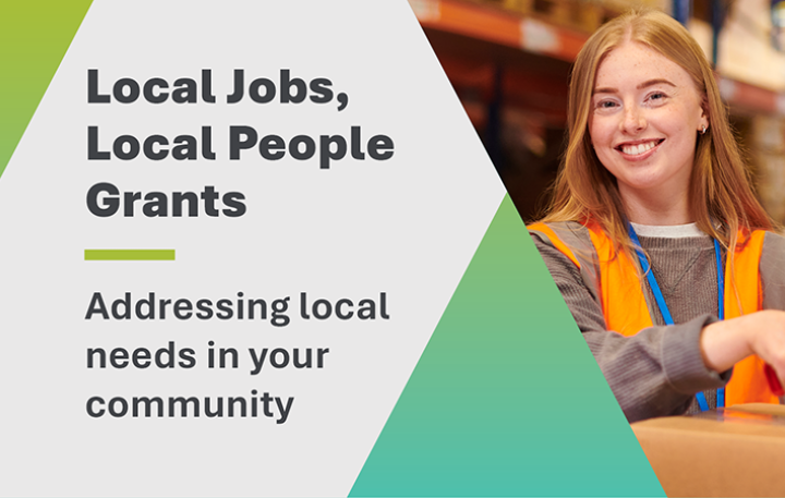 Mid-shot of a young woman in high-visibility orange workwear, smiling at the camera while taping the top of a cardboard box. On the left side of the frame is the title: 'Local Jobs, Local People Grants – Addressing local needs in your community'