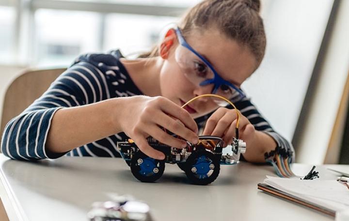 Girl with clear glasses building a small robot